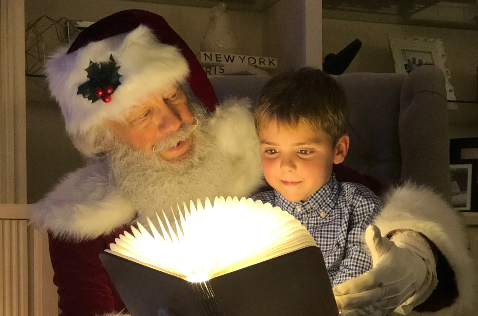 Santa sharing a glowing storybook with a young child